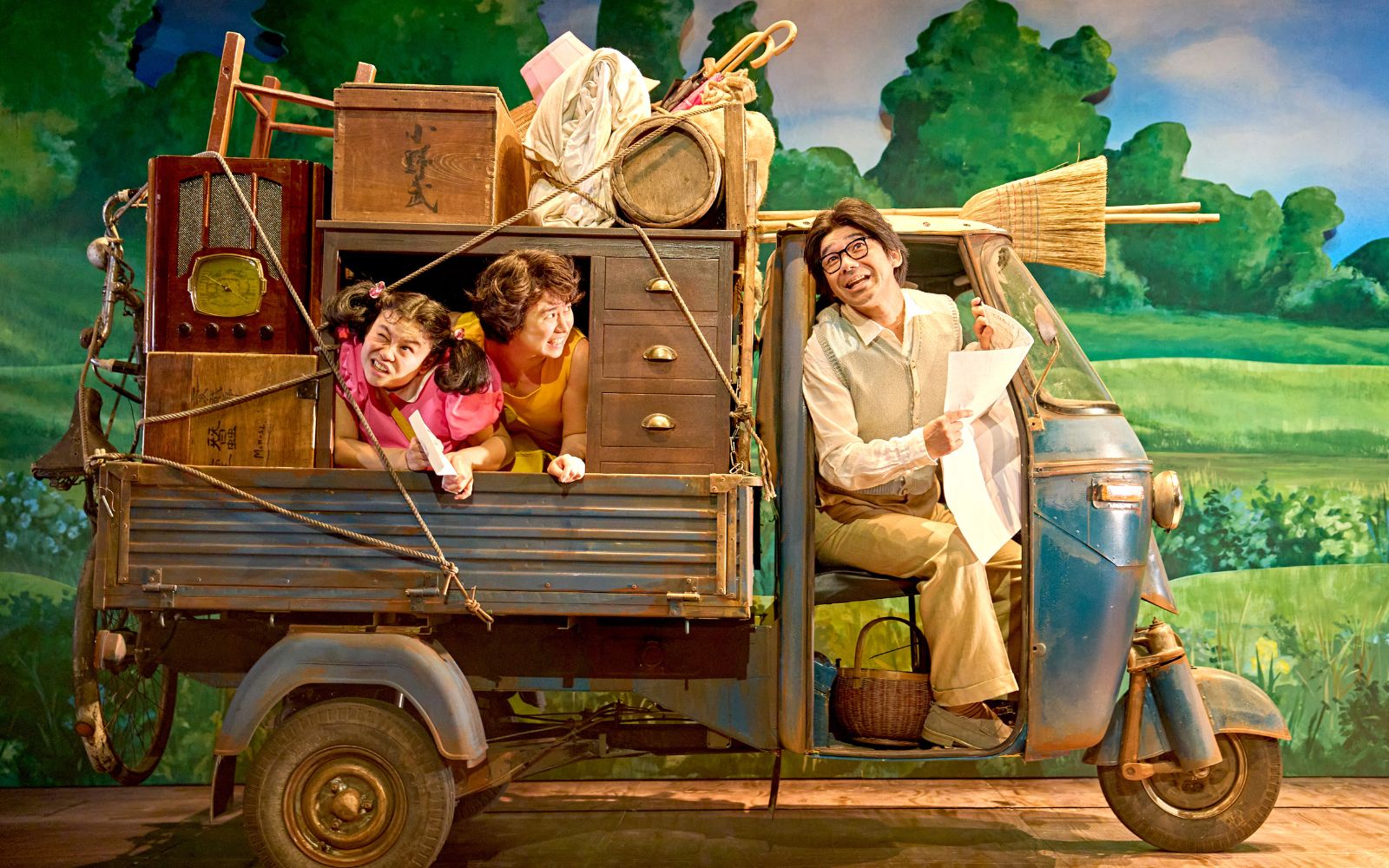 two children and man riding in a truck packed with furniture
