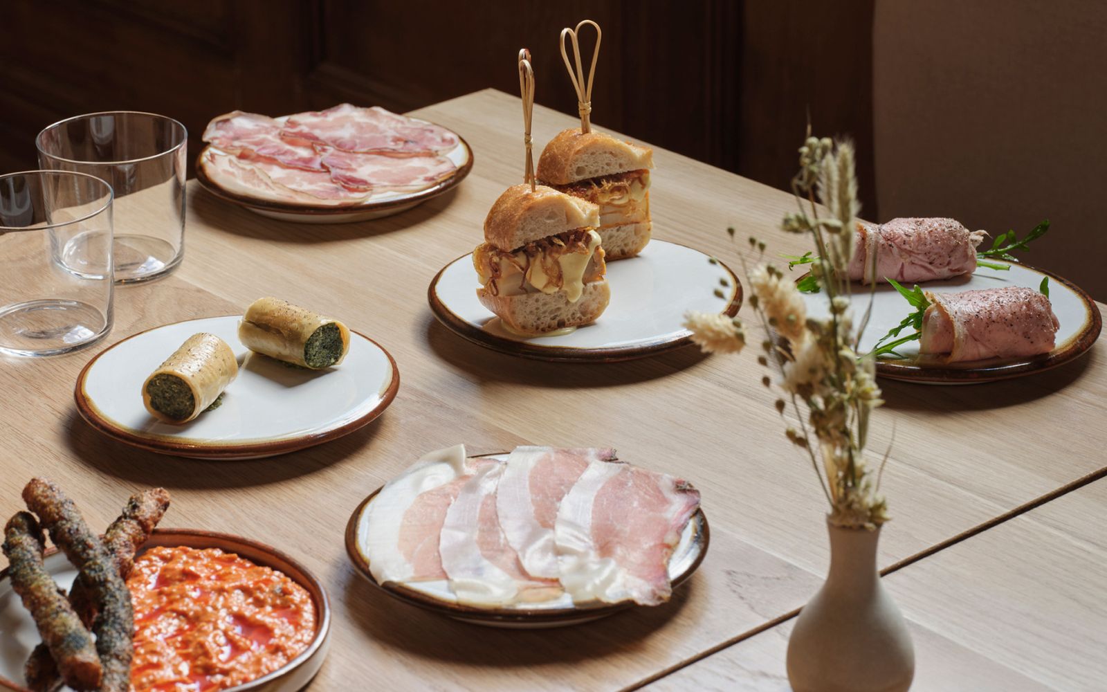 plates of buns, ham and croquettes on a wooden table