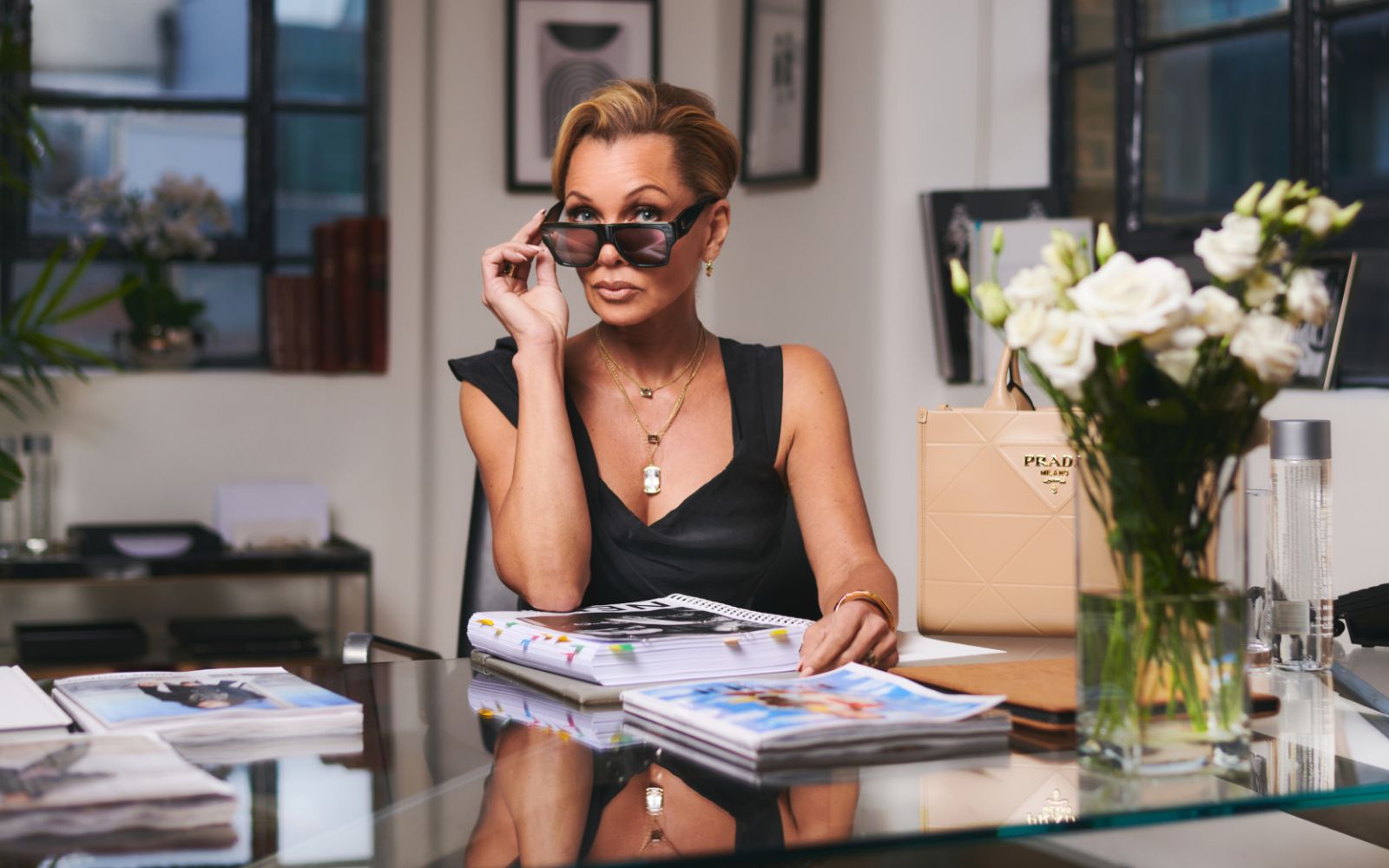 woman sitting at a desk looking over her sunglasses